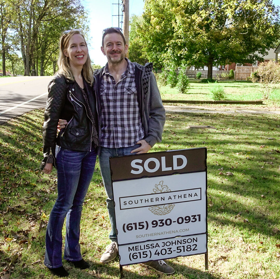 Joel and Michelle standing with Sold sign