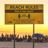 Social Distancing Sign on Florida Beach with crowd in background not complying in 2020 © Joel Hartz