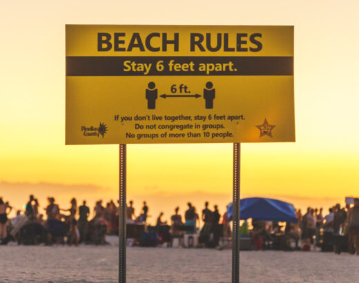 Social Distancing Sign on Florida Beach with crowd in background not complying in 2020 © Joel Hartz