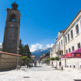 Pirin street in Bankso Bulgaria on sunny day with Orthodox church tower and mountains in distance