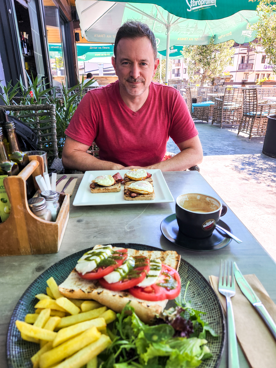travel blogger Joel Hartz with a plate of breakfast food at outside patio in Bansko Bulgaria