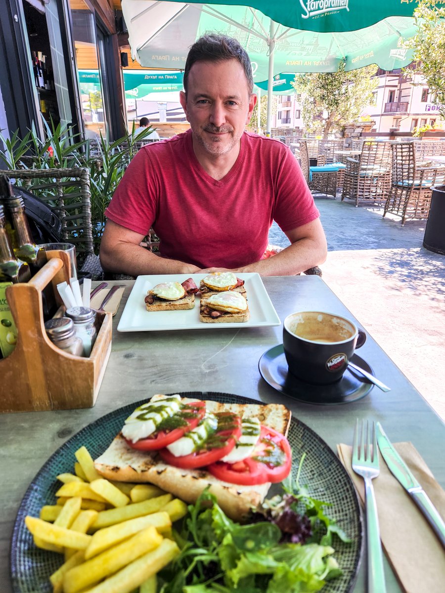 travel blogger Joel Hartz with a plate of breakfast food at outside patio in Bansko Bulgaria