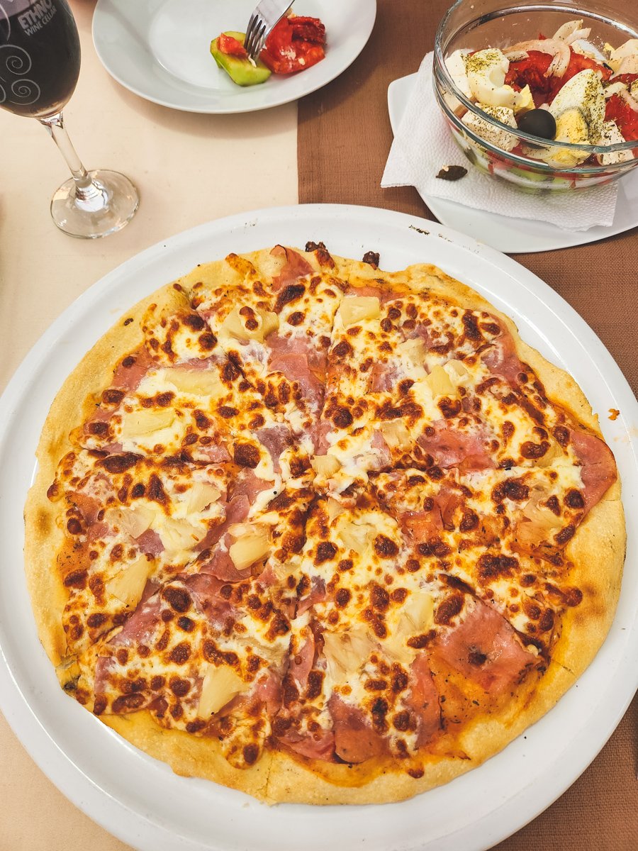 overhead shot of Hawaiian pizza and shopska salad