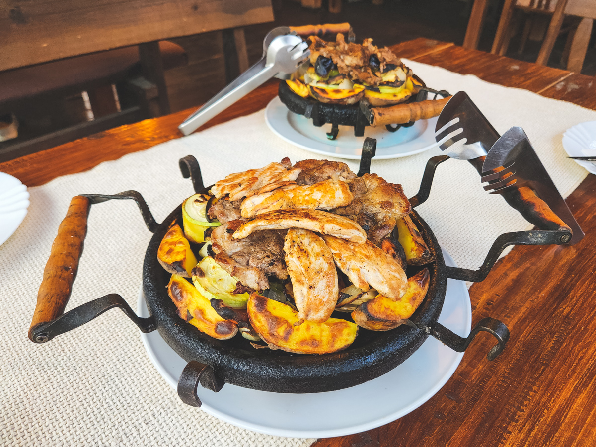 Traditional Bulgarian Sache with chicken, pork and vegetables served on cast iron skillet with handles
