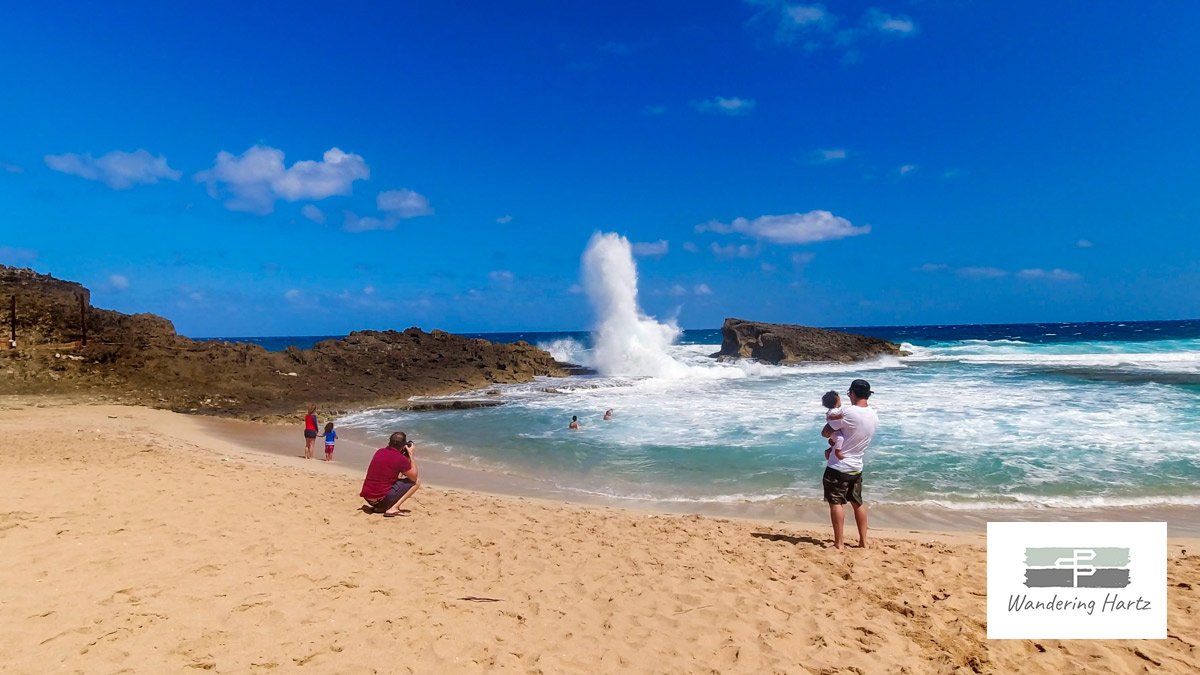 People watching the waves crashing against the reef at Playa La Poza del Obispo, Arecibo, Puerto Rico