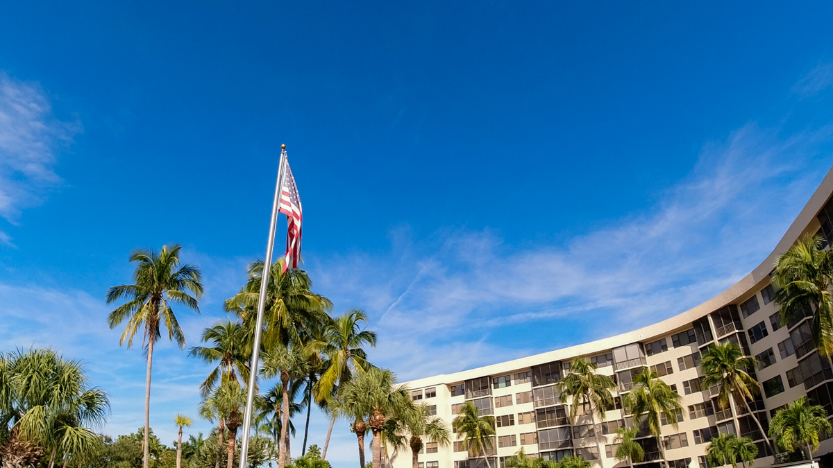 American flag in front of Harbor Towers Yacht & Racquet Club on clear day  © Joel Hartz