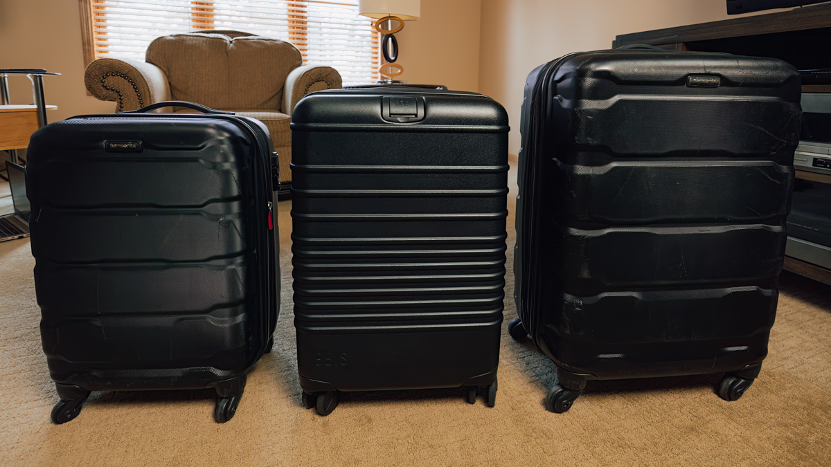 three  black suitcases in row compared to each other. Beis Carry-on Roller luggage (middle) compared to Samsonite Omni 20" and 24" © Joel Hartz