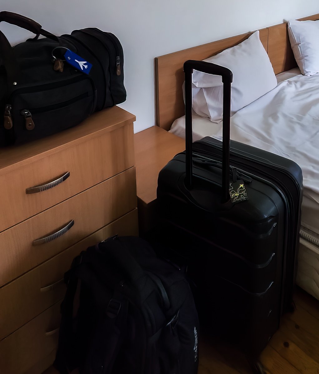 Luggage in Hotel room. Duffel bag on dresser, hardside spinner suitcase with handle extended