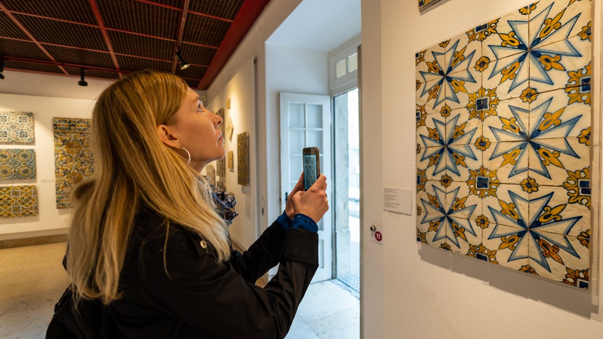 woman taking photo on her phone of Portuguese tile arrangement at the National Tile Museum Lisbon