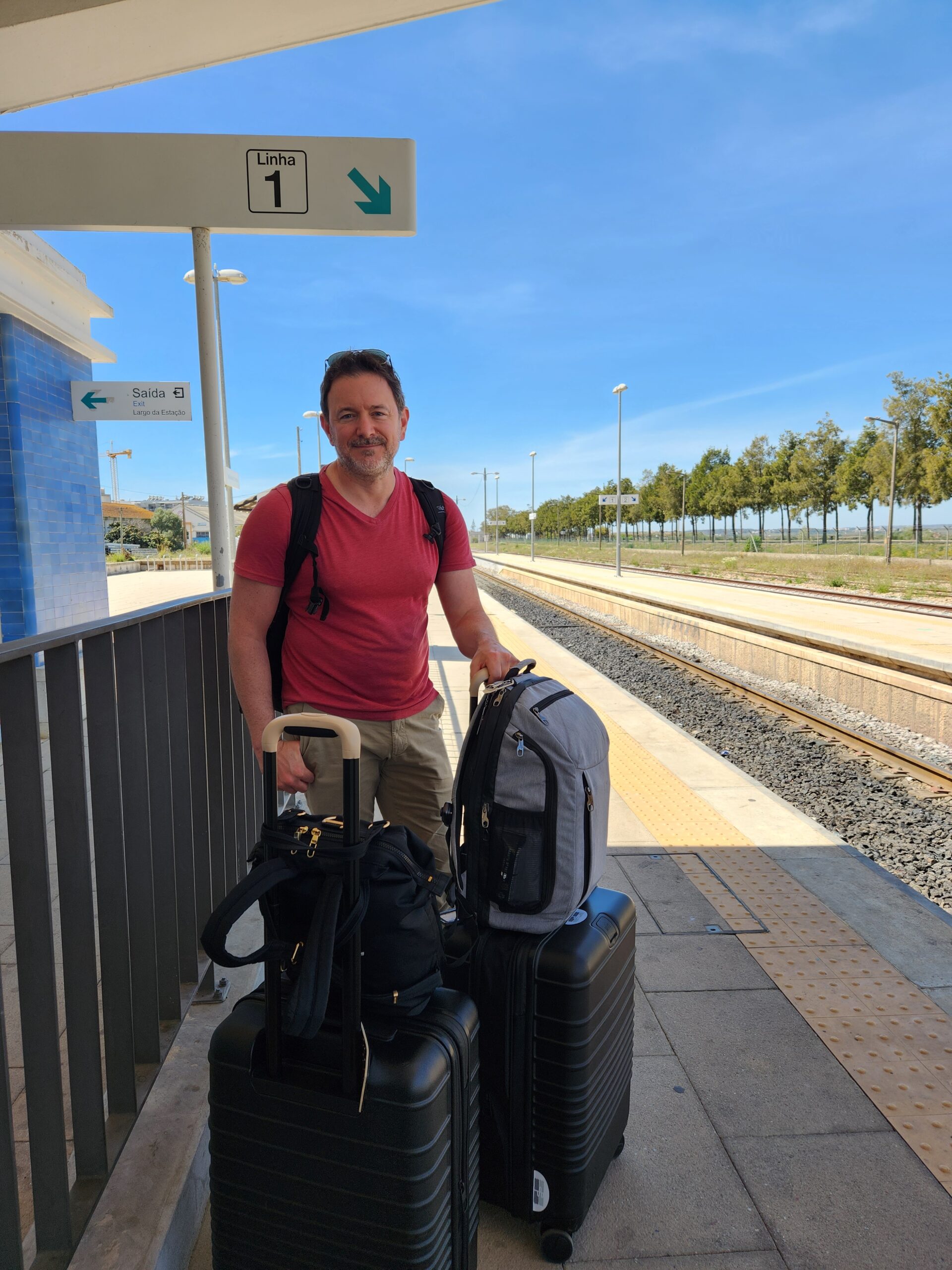 Joel awaiting a train with luggage in Portugal