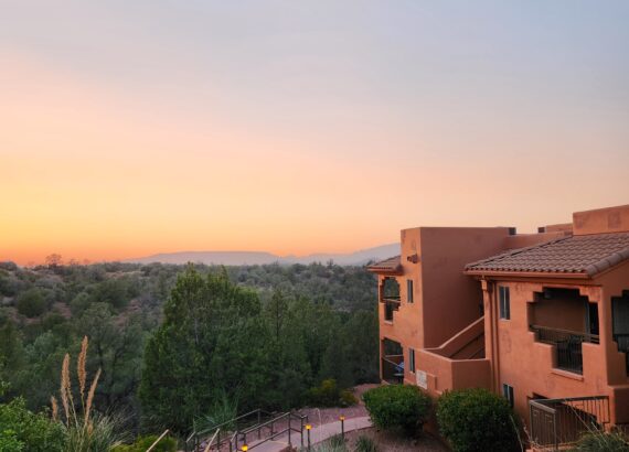 orange and pink sunset at sedona summit hilton vacation club looking down at lighted sidewalk leading down to brown building.