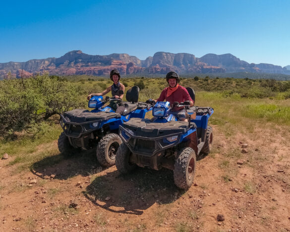 man and woman on blue atvs in sedona arizona with blue sky and red rock backdrop