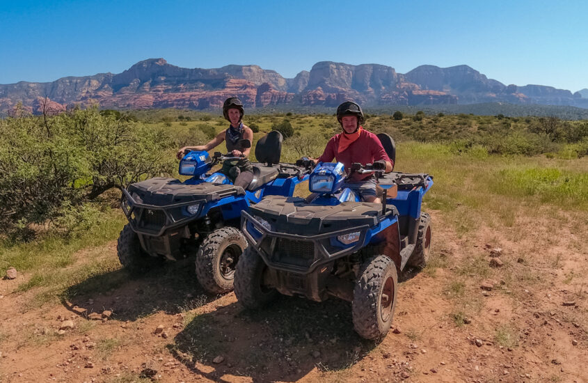 man and woman on blue atvs in sedona arizona with blue sky and red rock backdrop