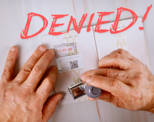 a person's hands stamping a passport with the word denied above