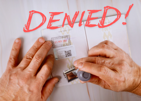 a person's hands stamping a passport with the word denied above