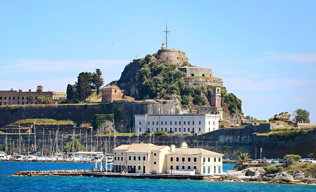 a stone fortress on a hill next to a body of water, Corfu Greece.