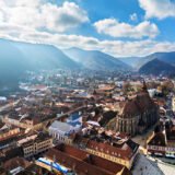 Aerial drone view of Black Church in Brasov city old center in autumn season. Mountains and blue sky with clouds. Romania