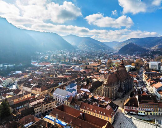 Aerial drone view of Black Church in Brasov city old center in autumn season. Mountains and blue sky with clouds. Romania