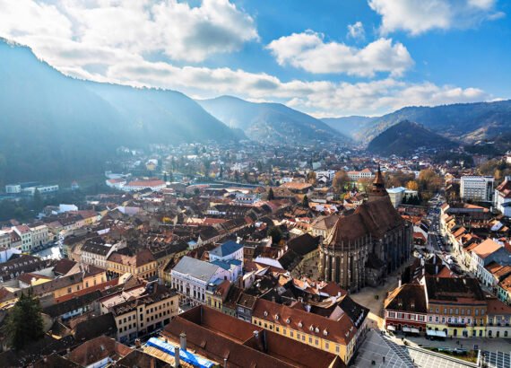 Aerial drone view of Black Church in Brasov city old center in autumn season. Mountains and blue sky with clouds. Romania