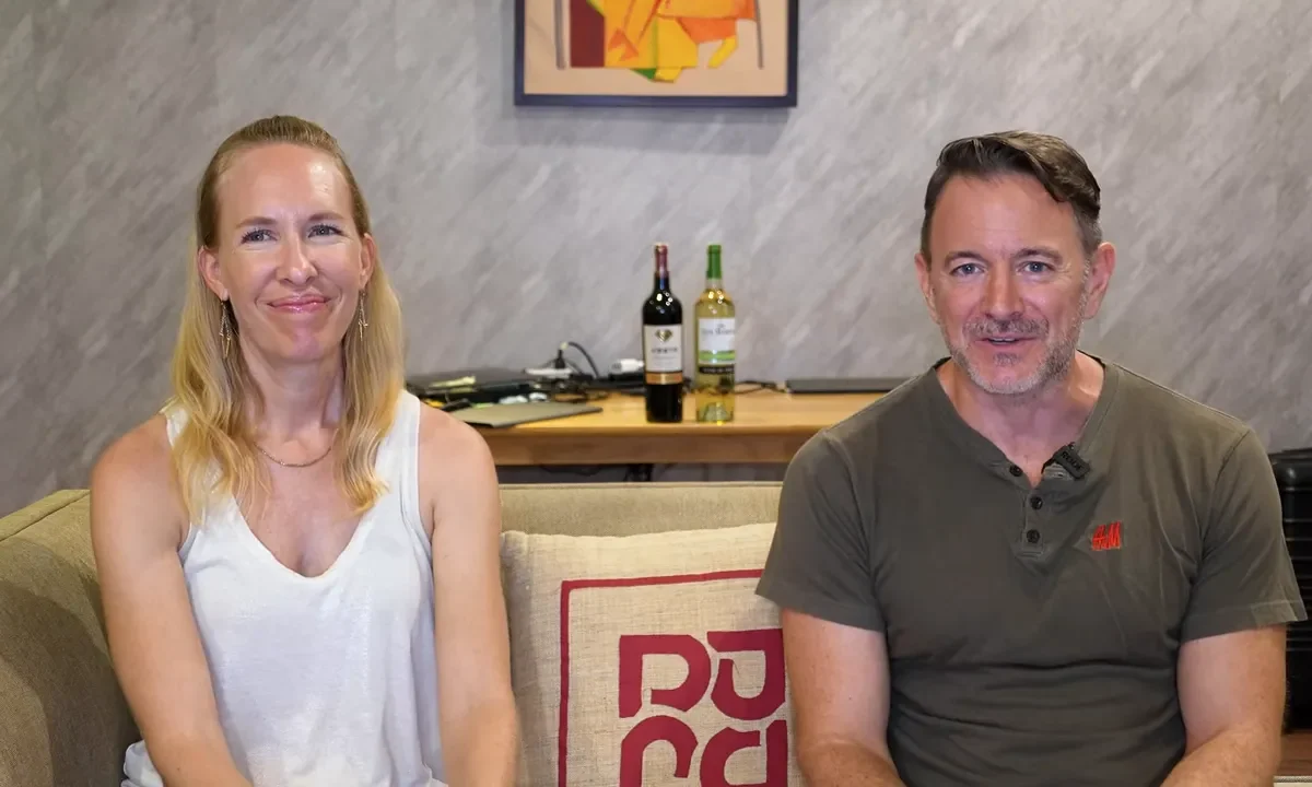 two people sitting on a couch talking to the camera